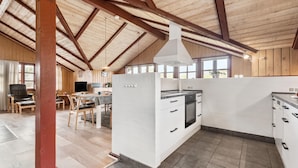 Une cuisine spacieuse avec des meubles blancs, un îlot central et une grande fenêtre qui laisse entrer la lumière naturelle.
