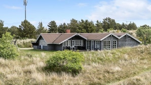 Une cabane rustique dotée d’un toit en pente, de nombreuses fenêtres et d’une cheminée.