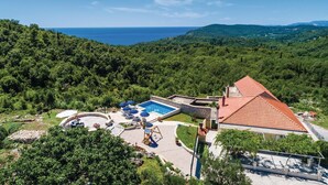 A villa with a swimming pool, outdoor seating, and a view of the sea.