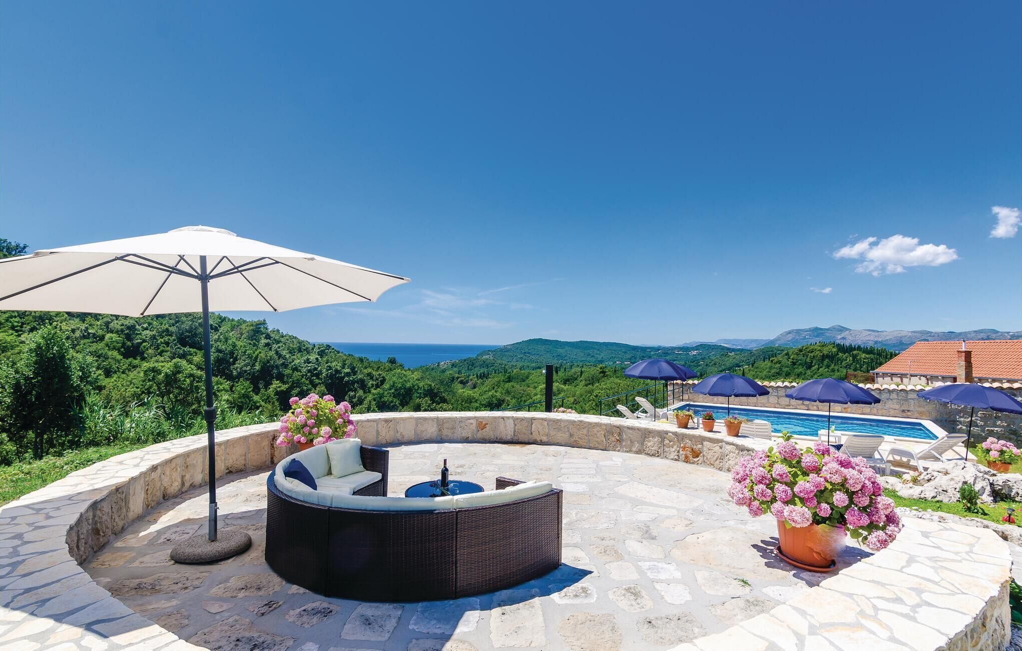 Ein kreisförmiger Sitzbereich im Freien mit Pool, umgeben von Steinboden und Kübelpflanzen.