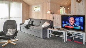 A cozy living room with a grey sofa, a black leather chair, and a flat-screen TV on a white stand. - Gorgeous home in Oksbøl with sauna (Oksbøl)