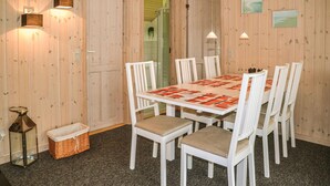 A dining area with a white table and chairs, a patterned tablecloth, and wooden walls. - Gorgeous home in Oksbøl with sauna (Oksbøl)