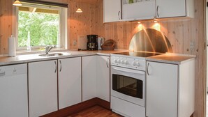 A compact kitchen with white cabinetry, a stainless steel range hood, a built-in oven, and a window providing natural light. - Gorgeous home in Oksbøl with sauna (Oksbøl)