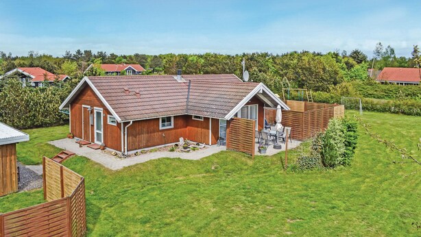 A single-story wooden house with a sloped roof, a front porch, and a fenced backyard. - Gorgeous home in Oksbøl with sauna (Oksbøl)