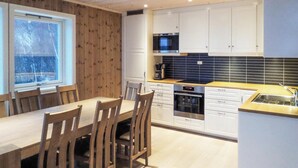 Eine moderne Küche mit weißen Schränken, einer schwarzen Mikrowelle und einem Holzespeisetisch mit Stühlen.