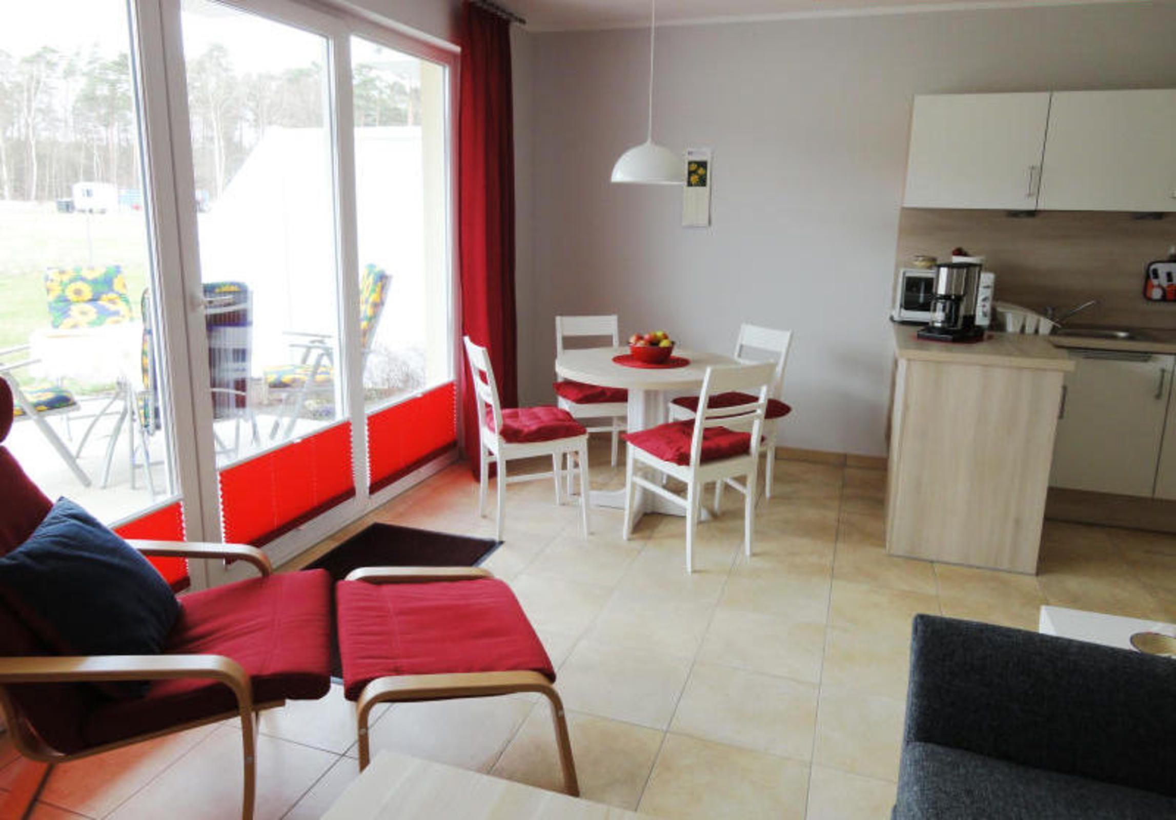 Une pièce comprenant une table à manger, des chaises, un coin cuisine et un espace salon avec un canapé et des fauteuils.