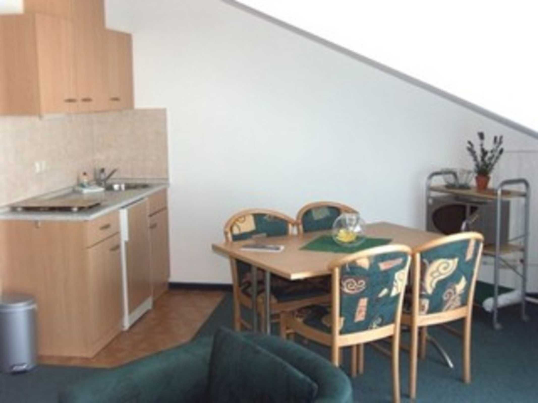 A compact kitchen with wooden cabinets and a dining area with a table and chairs.