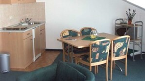 Une cuisine de taille réduite, dotée de meubles en bois et d’un coin repas avec une table et des chaises.