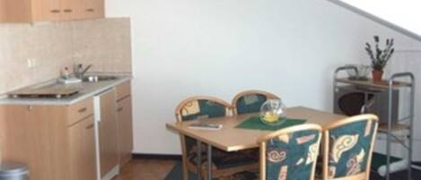 A compact kitchen with wooden cabinets and a dining area with a table and chairs.
