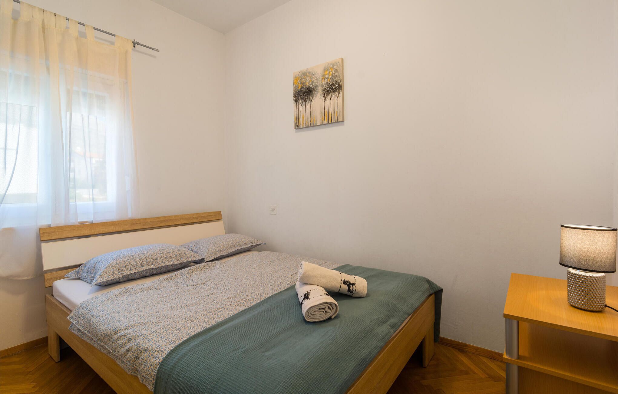 Una camera da letto con un letto, un comodino con una lampada e un quadro appeso al muro.