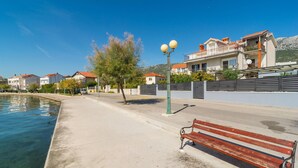 A waterfront promenade with a bench, lamp post, and residential buildings.