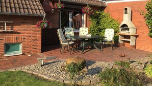 A patio with a brick fireplace, outdoor seating, and a pizza oven.
