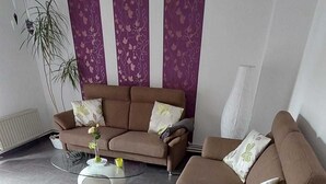 A modern living room with a brown sofa set, a glass coffee table, and a decorative plant.