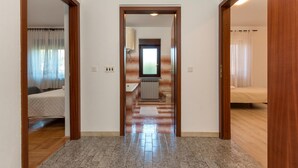 A hallway leading to a bathroom with a toilet, a sink, and a window. There is a bed visible in the adjacent room. - Amazing apartment in Pula (Pula)