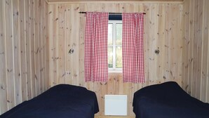A room with wooden walls, a window with red and white checkered curtains, and two dark-colored beds. - Amazing home in Sjusjøen with sauna (Sjusjøen)