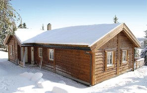 Situated in a serene snowy landscape, this cabin features a front door, windows, and a chimney.