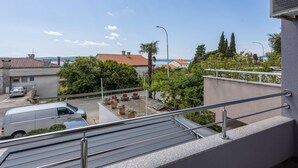 A residential area with a view of the sea, a white van parked on the street, and a balcony with a metal railing. - Beach front apartment in Crikvenica (Crikvenica)