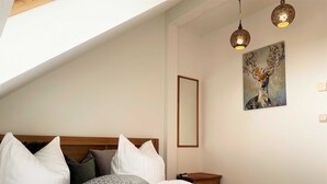 Une chambre à coucher avec une tête de lit en bois, du linge de lit blanc et un tableau accroché au mur.
