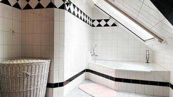 A modern bathroom with a freestanding bathtub, a wicker basket, and a pink rug.
