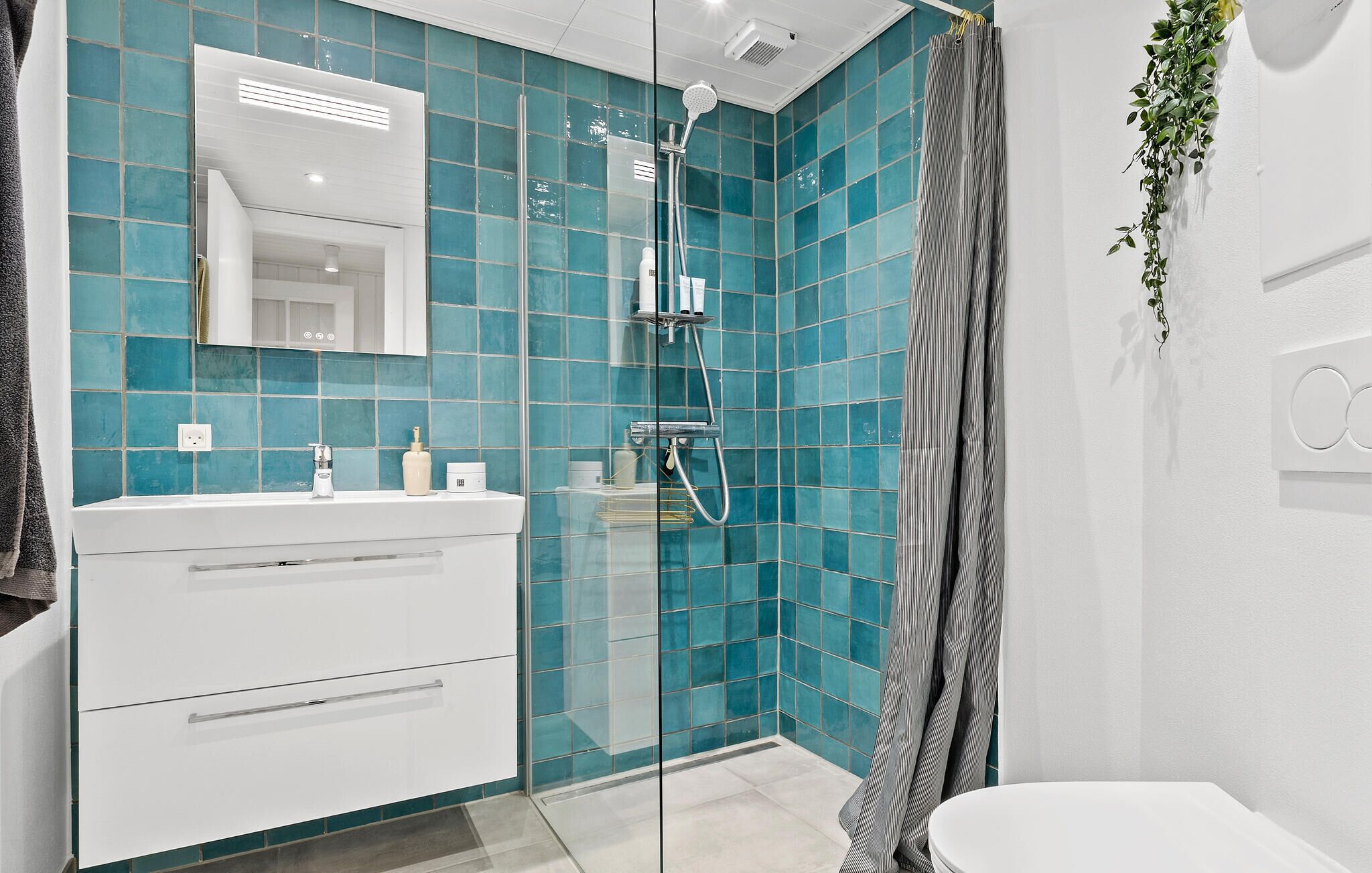 A modern bathroom with a glass shower enclosure, white vanity, and a large mirror.