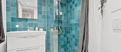 A modern bathroom with a glass shower enclosure, white vanity, and a large mirror.