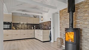 Eine moderne Küche mit Holzschränken, einem schwarzen Herd und einer Steinwand.