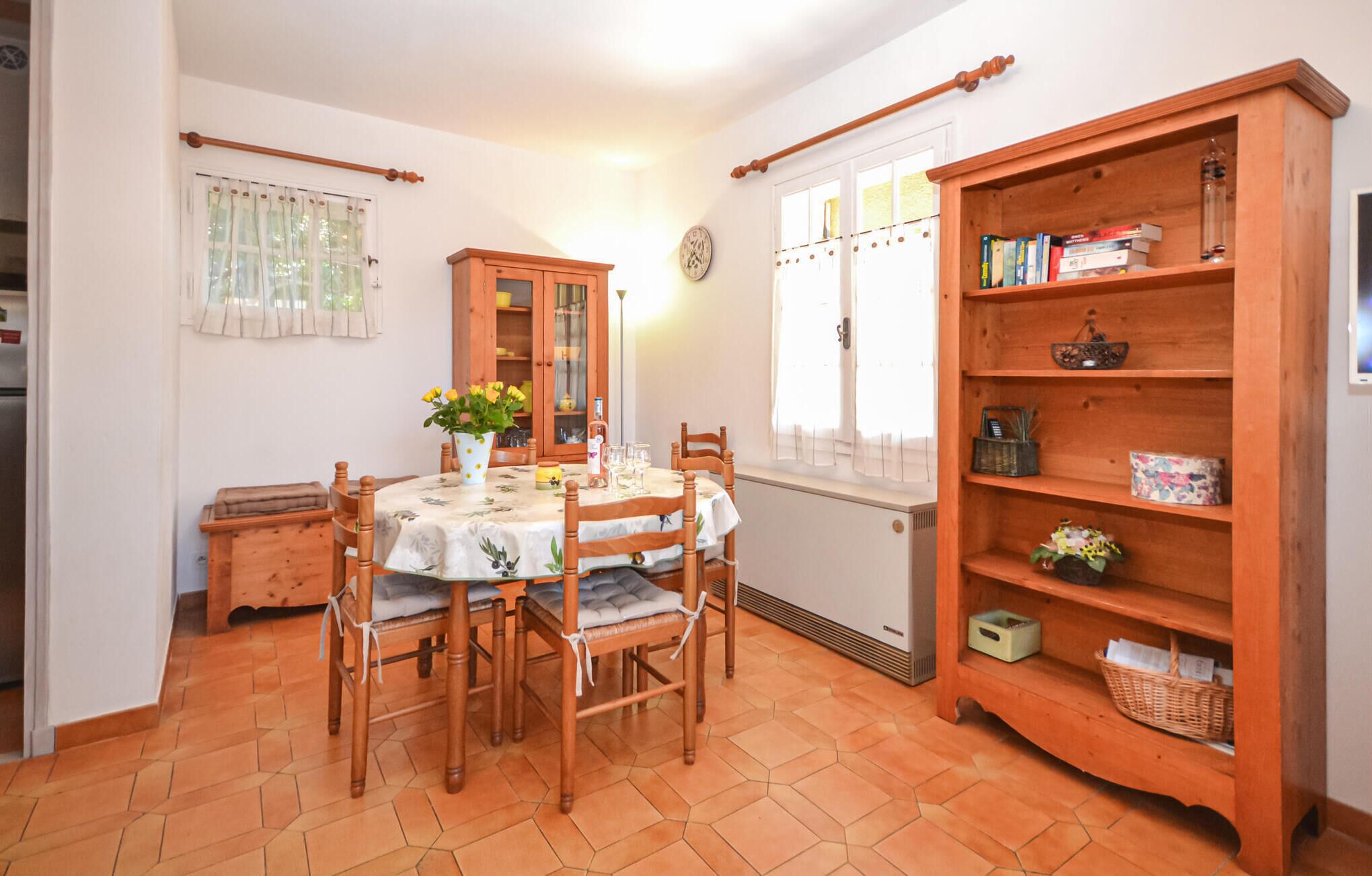 A dining area with a wooden table, chairs, a cabinet, and a window with curtains.