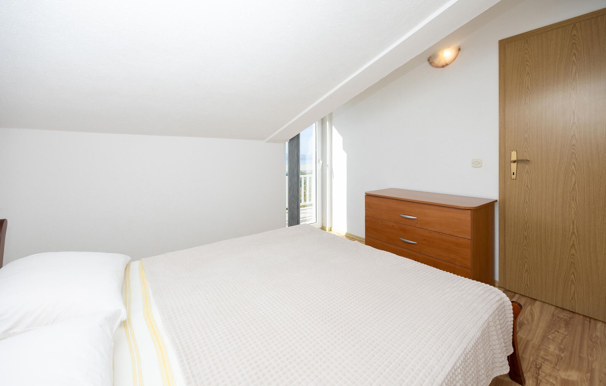 Ein Schlafzimmer mit einem Bett, einem Holzschrank und einer Tür.