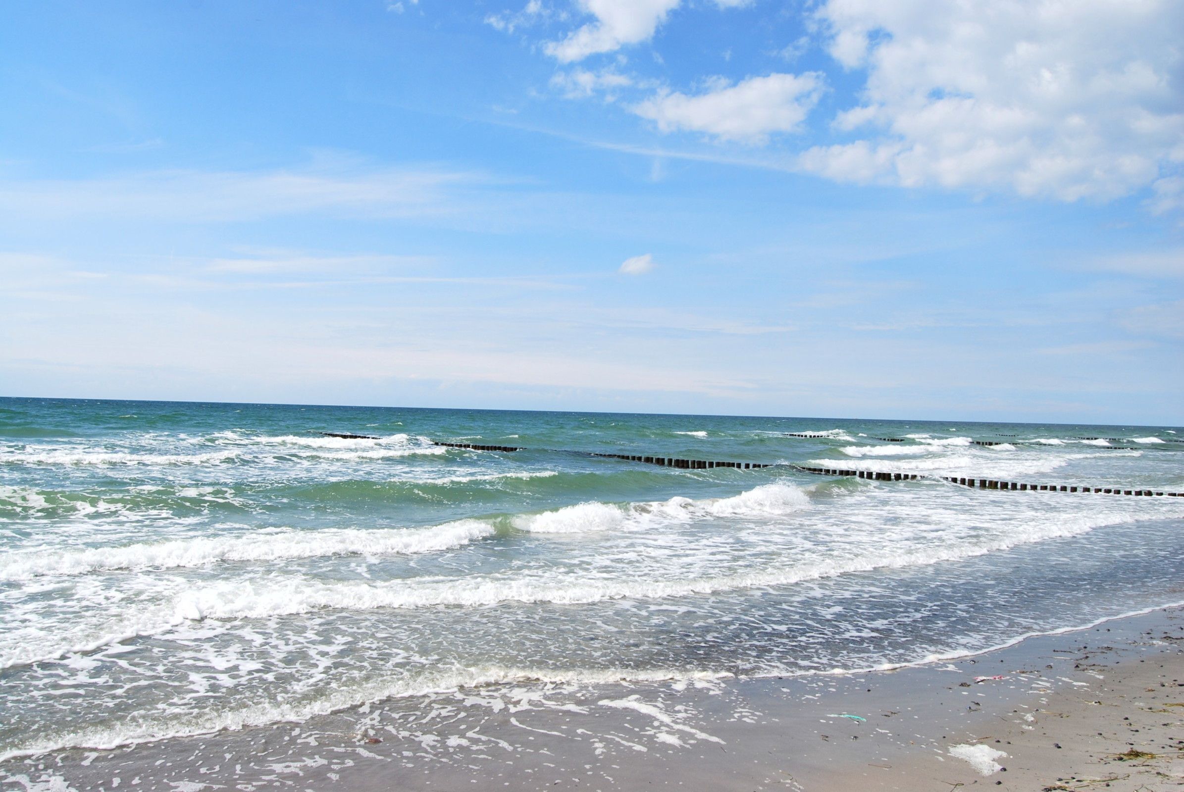 A beach with waves crashing onto the shore and a clear sky.