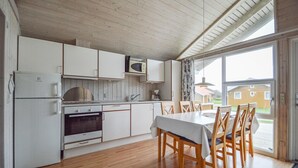 Eine moderne Küche mit weißen Schränken, einer Mikrowelle, einem Herd und einem Essbereich mit Tisch und Stühlen.