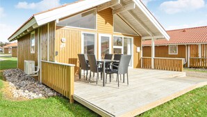 Eine Holzhütte mit einer Terrasse, einem Tisch und Stühlen sowie einem Fenster.