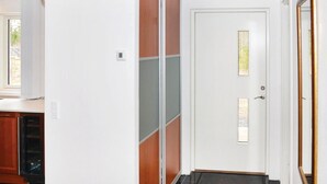 Un pasillo con una puerta blanca, una ventana pequeña y un timbre.