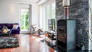 Una sala de estar moderna con chimenea, ventanas amplias, un sofá y una mesa de centro.