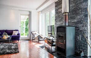 Una sala de estar moderna con chimenea, ventanas amplias, un sofá y una mesa de centro.