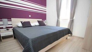 Une chambre à coucher bien rangée, avec un lit, des tables de chevet et une petite table de nuit.