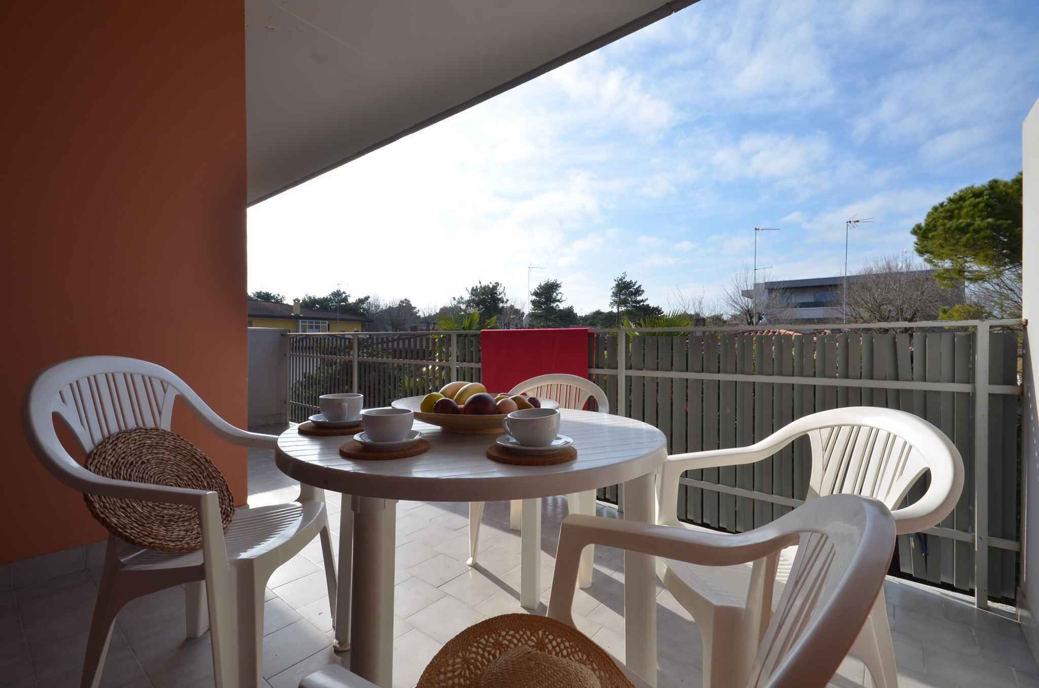 A balcony with a round table, white plastic chairs, and a wicker basket.