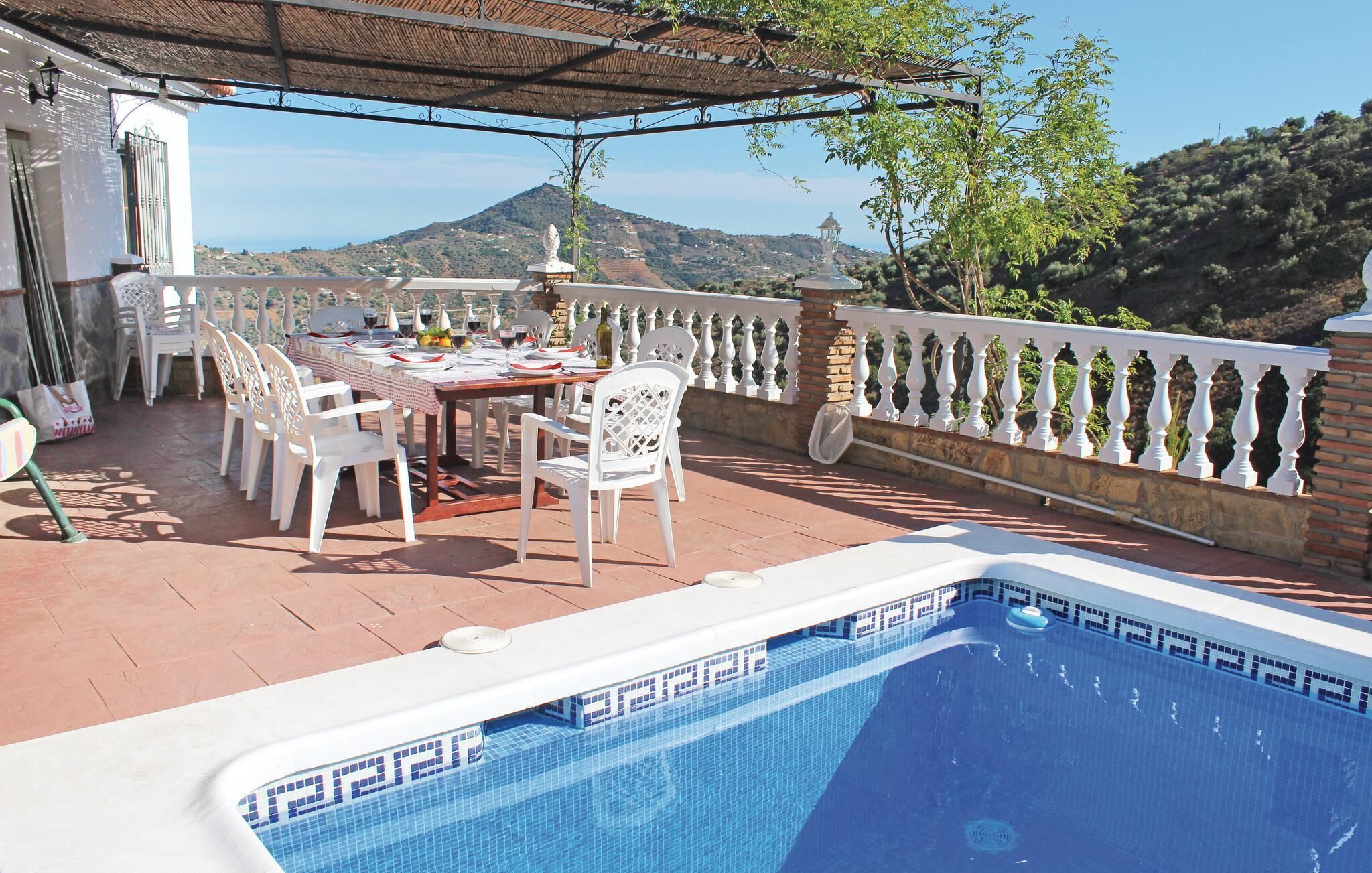 Une terrasse avec une piscine, une table à manger, des chaises et une vue sur les collines.