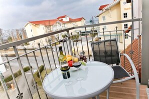 Ein Balkon mit Tisch für zwei Personen, einer Weinflasche und einer Obstschale.
