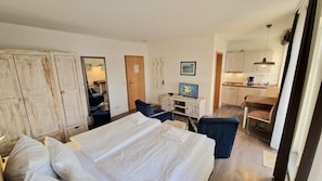 Une chambre d’hôtel équipée d’un lit, d’un bureau, d’une chaise, d’une télévision et d’une kitchenette.