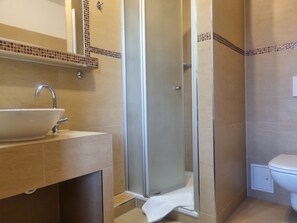 Ein Badezimmer mit Waschbecken, Spiegel, Dusche und Toilette.