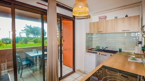 A modern kitchen with a dishwasher, a sink, and a dining area with a table and chairs. - Gorgeous apartment in Moriani Plage (Moriani Plage)