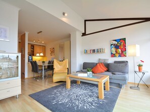 A modern living room with a sofa, coffee table, and a dining area with chairs and a table.