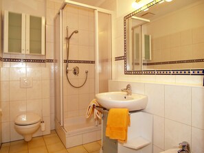 Un baño con inodoro, ducha, lavabo y espejo.