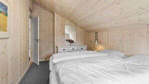 Een slaapkamer met een houten plafond, een wit bed, een kast en een spiegel.