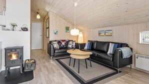 Een gezellige woonkamer met een zwarte leren bank, een houten salontafel en een houtkachel.