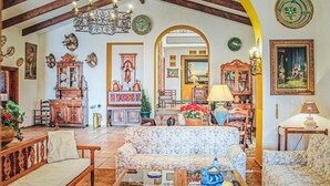 Un salon chaleureux avec un canapé à motifs floraux, des meubles en bois et une table basse en verre.