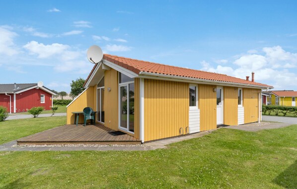 A yellow single-story building with a red-tiled roof, a satellite dish, and a small deck area. - Friedrichskoog-Deichblick 20 (Friedrichskoog)