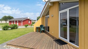 A yellow building with a wooden deck, a satellite dish, and a sliding glass door. - Friedrichskoog-Deichblick 20 (Friedrichskoog)