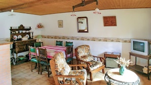Un comedor con mesa de madera, sillas y televisor.