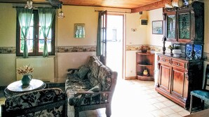 Una sala de estar acogedora con un sofá, una mesa con un florero y un mueble con objetos decorativos.